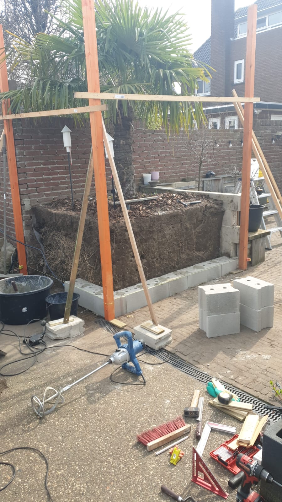 Plantenbak in aanbouw — opmetselen van betonblokken rondom palmboom